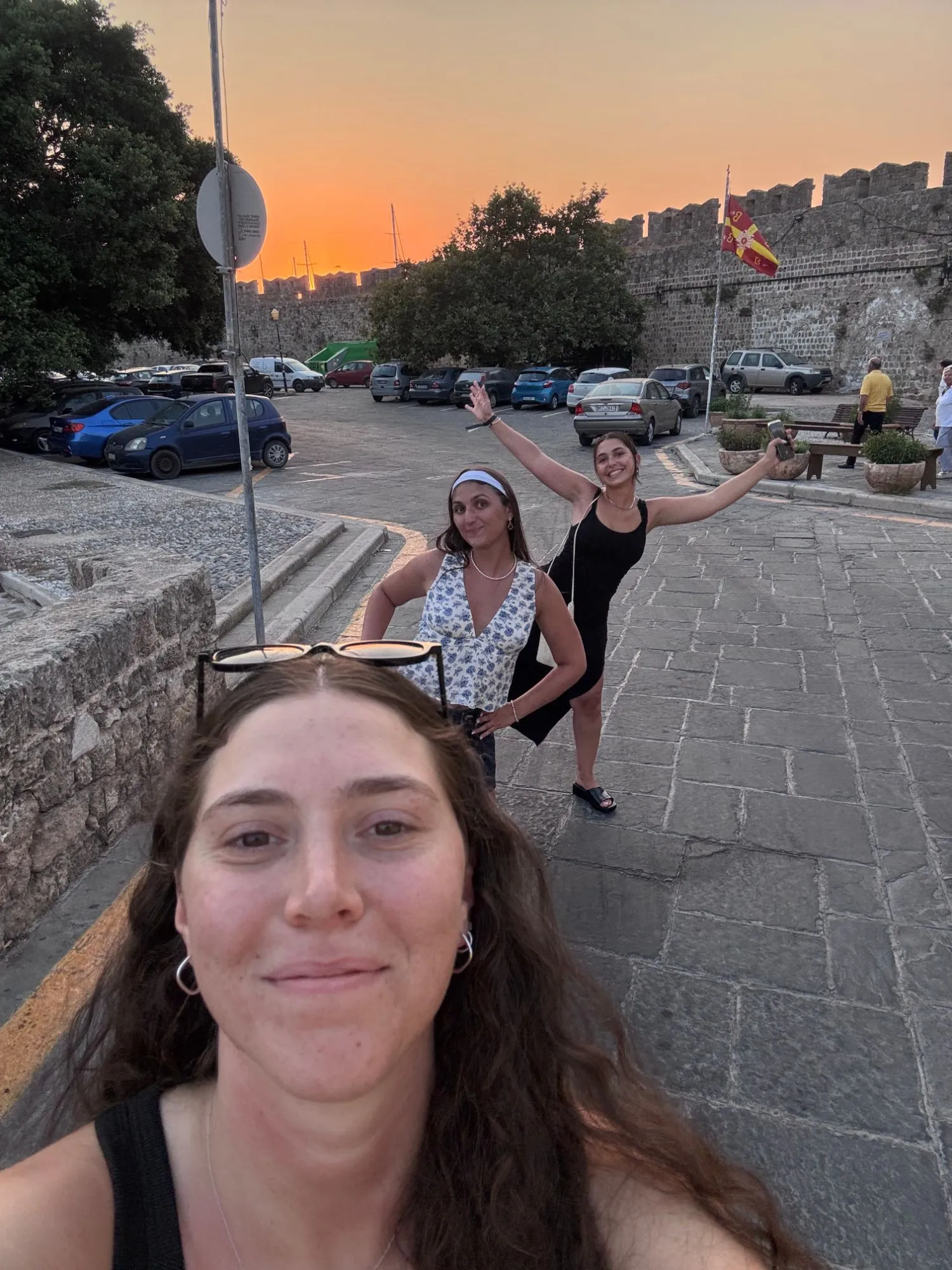 Dana and two other people on a cobbled street at sunset, beside a stone wall